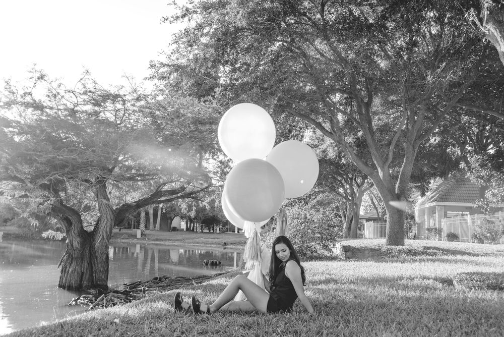girl holding balloons sitting down on the floor. quinceañera photo session. XV photographer