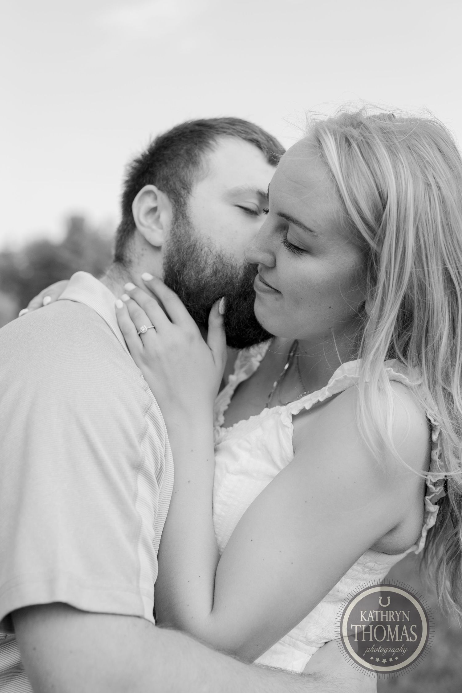 A romantic black and white portrait of a loving couple sharing an intimate moment outdoors.
