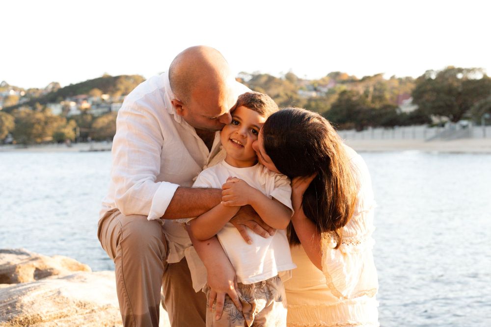 Dad and Mom kissing their son during golden hour family photoshoot in sydney