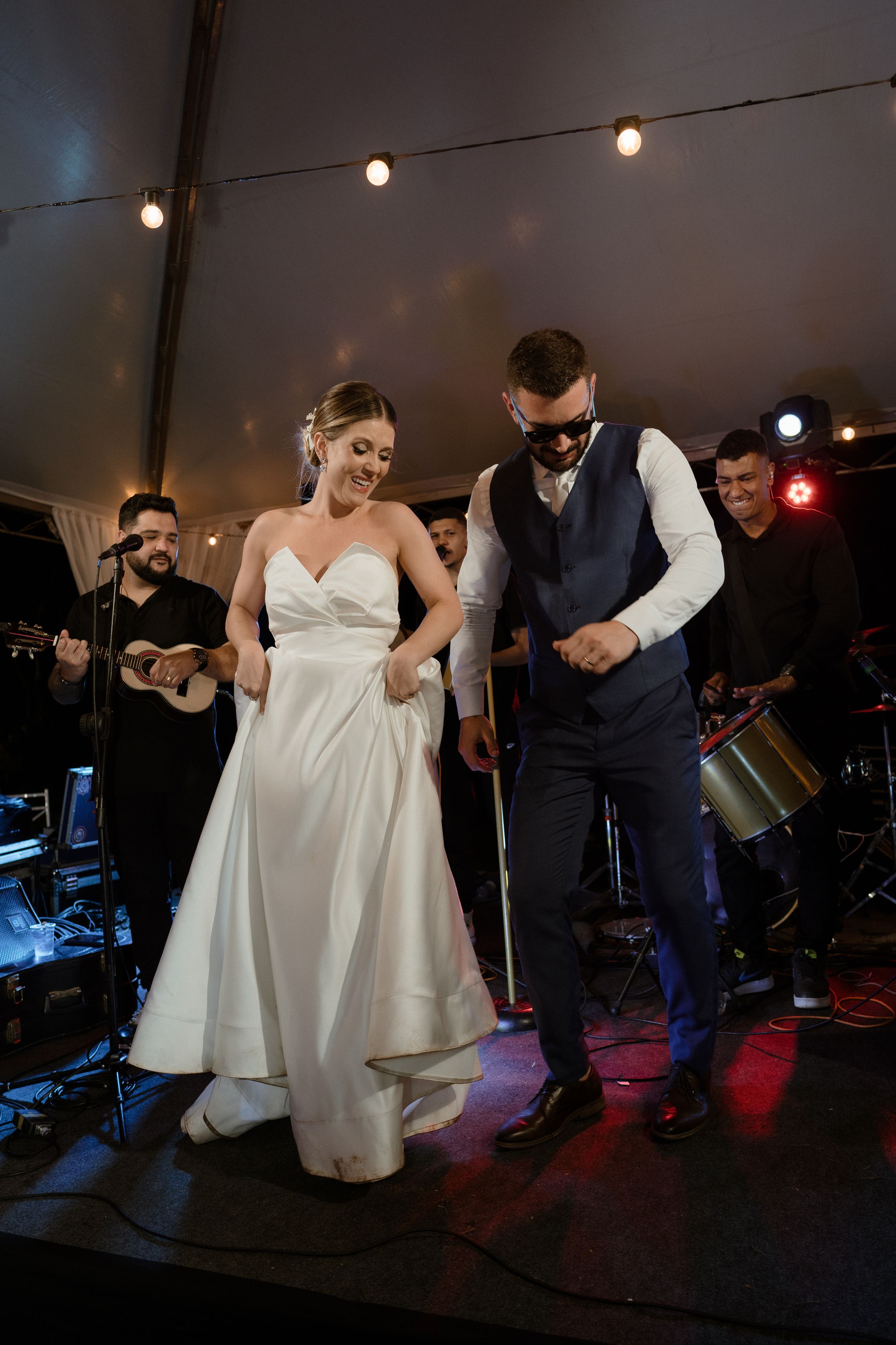Wedding couple dancing together on stage with live band performing in background.
