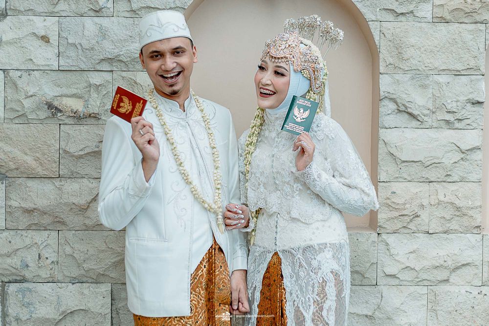 Happy couple in traditional wedding attire displaying their official documents.