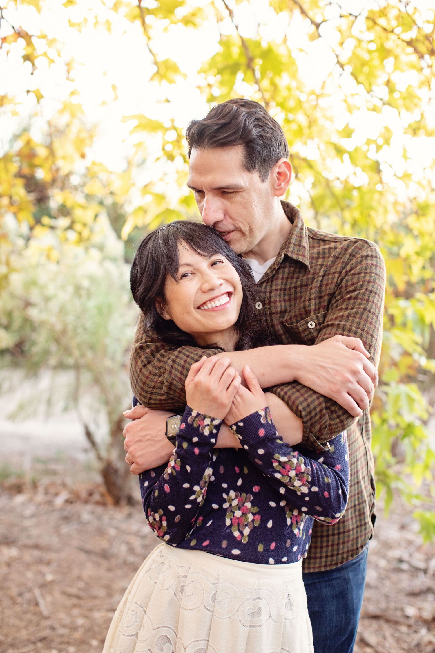 Couple embracing outdoors in autumn with golden leaves in background.