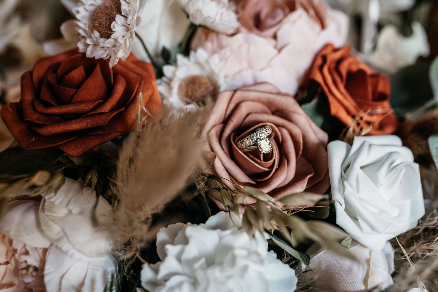 Close-up of a romantic wedding bouquet with burgundy, blush pink, and white roses against a dark background.