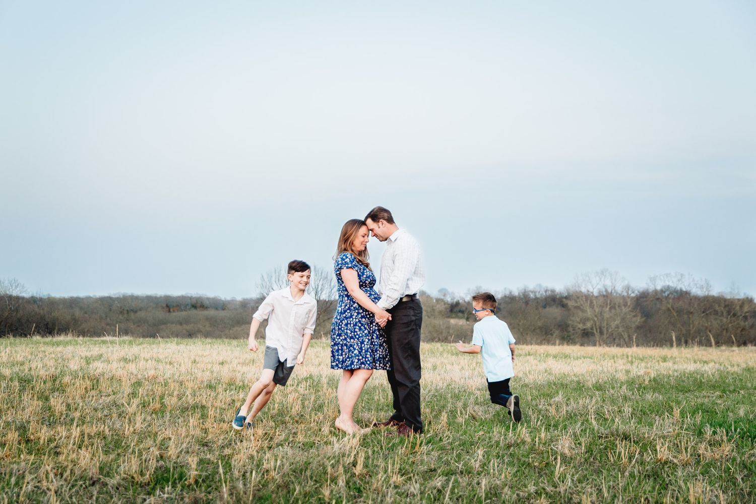 children running around their dad and expecting mother