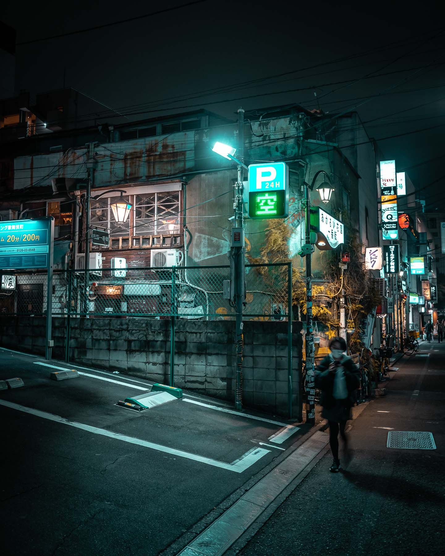 Moody urban alleyway with green neon signs and parking indicators glowing in the darkness.
