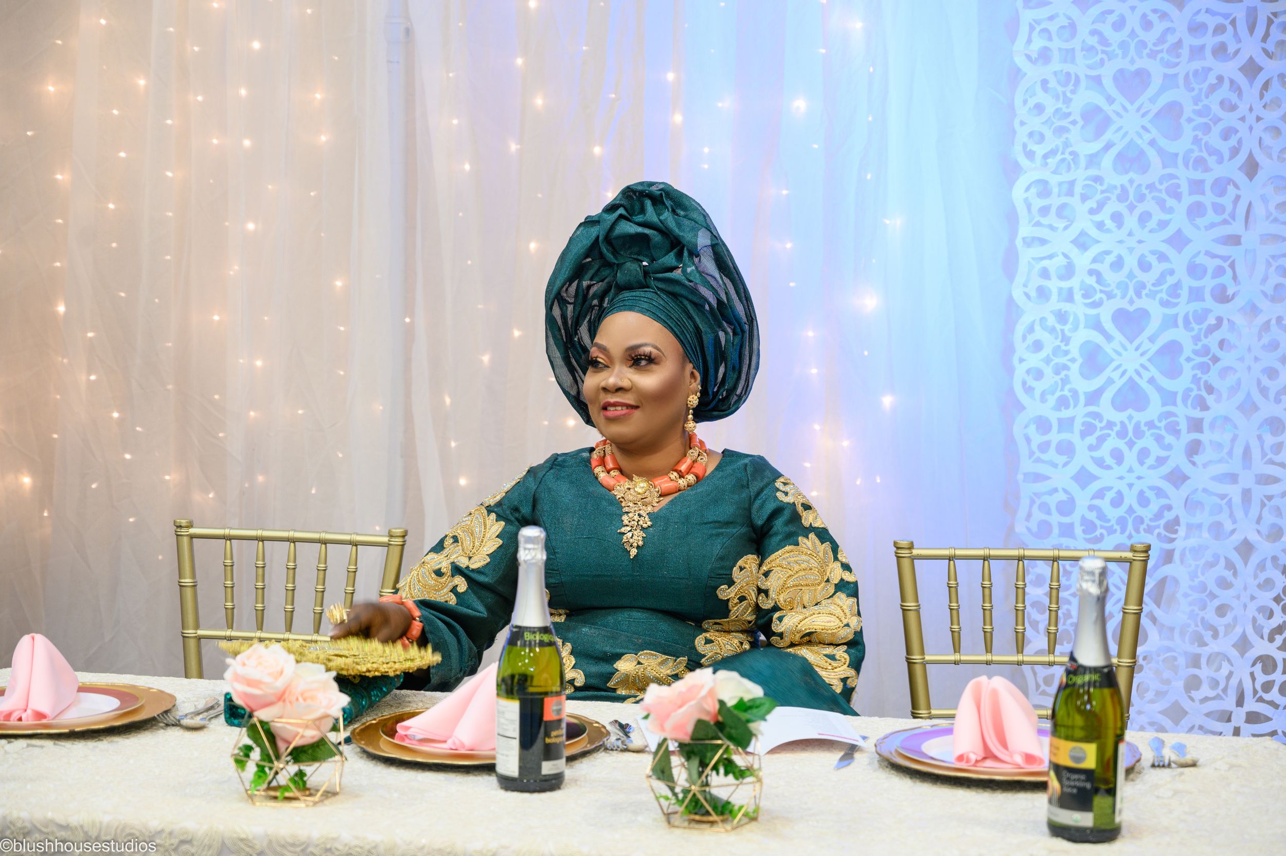 Elegant table setting with woman in green and gold attire surrounded by twinkle lights.