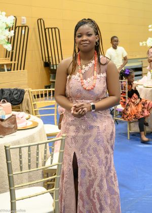 Guest in pink sequined gown standing near dining table at formal event.