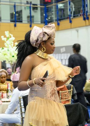 Guest in yellow tulle gown and ornate headpiece at formal celebration.