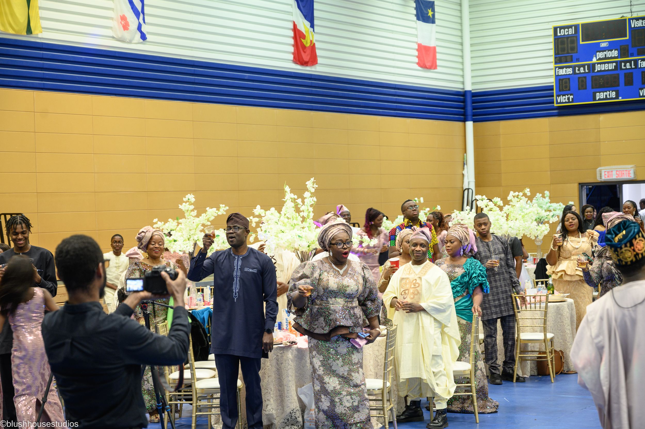 Celebration in a gymnasium with decorated tables and festive crowd.