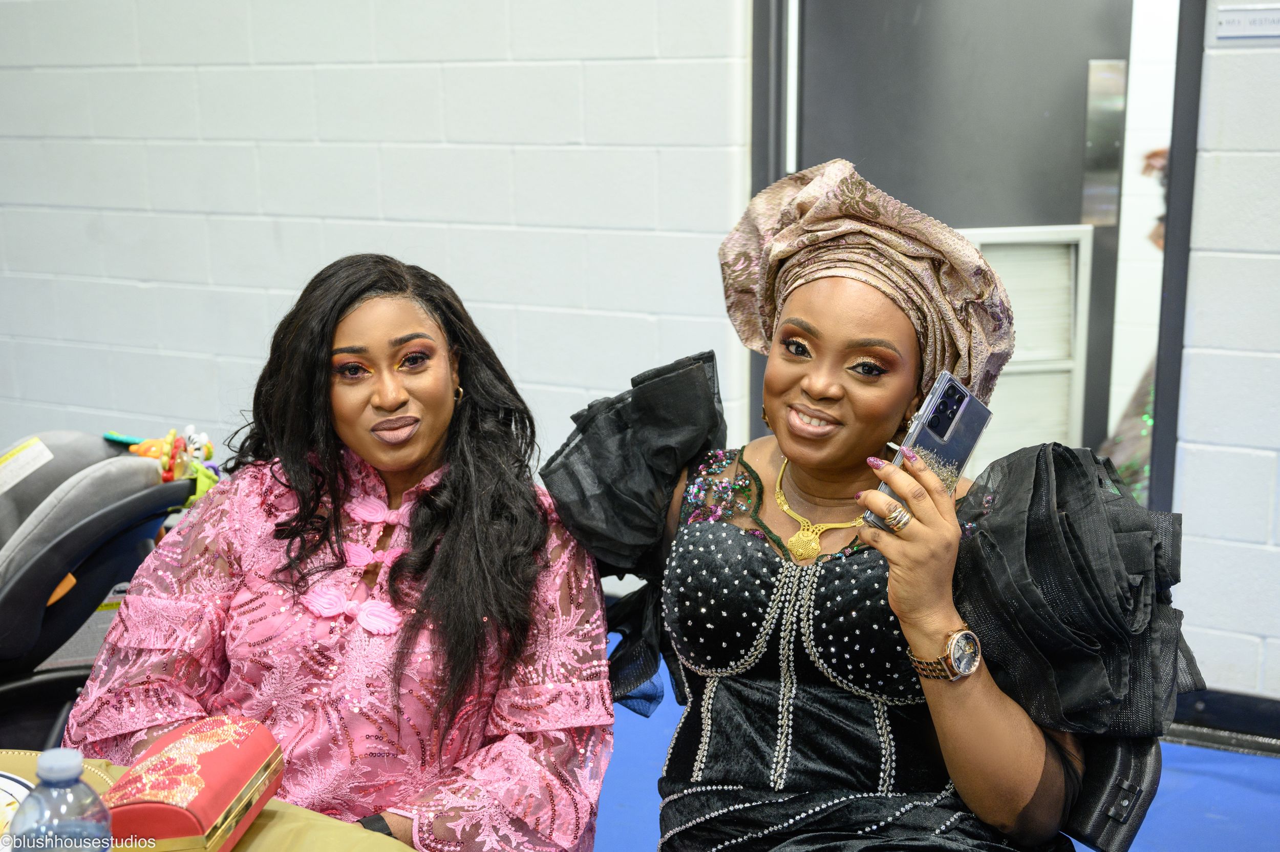 Two attendees in formal attire backstage at cultural celebration.
