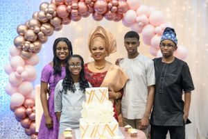 Group photo under pink and gold balloon arch at formal celebration.