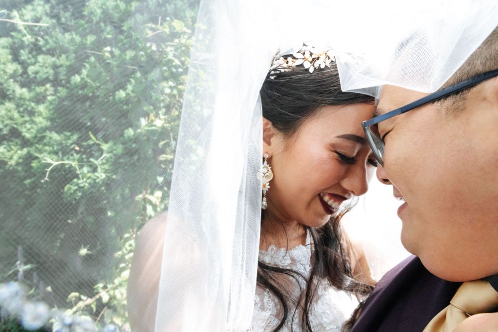 Romantic couple sharing intimate moment under sheer white curtains.