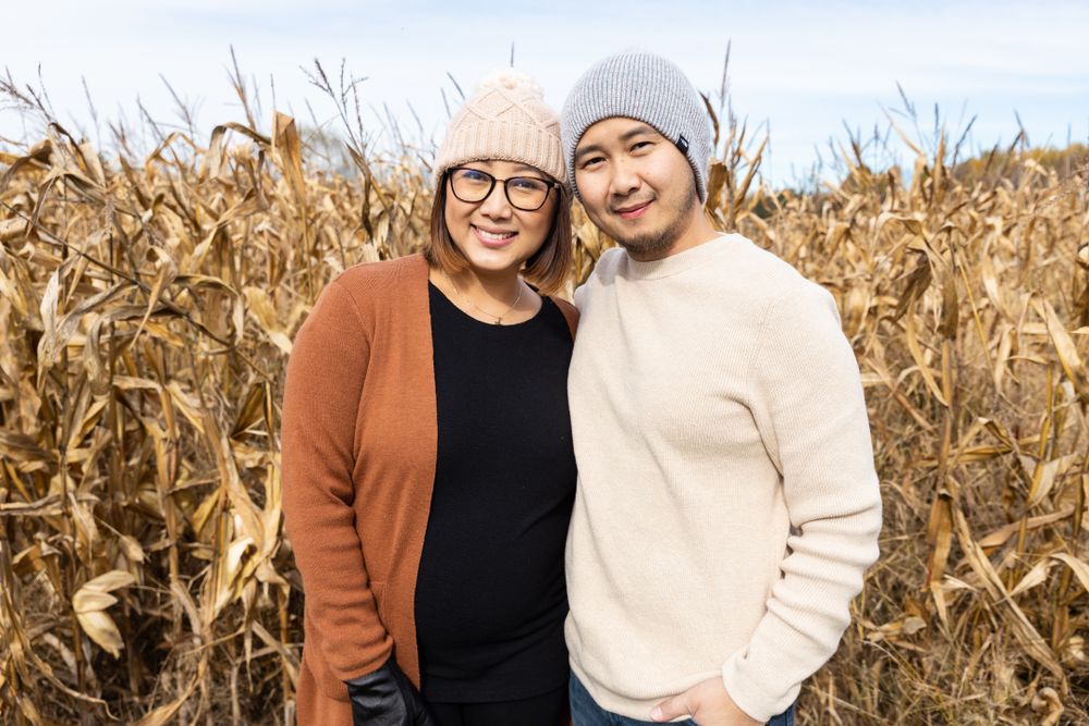 Couple taking casual engagement photos in a golden cornfield during autumn.