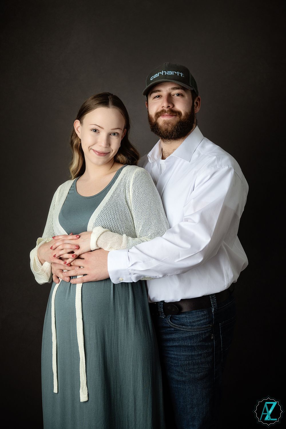 Intimate maternity studio portrait with couple in casual attire.