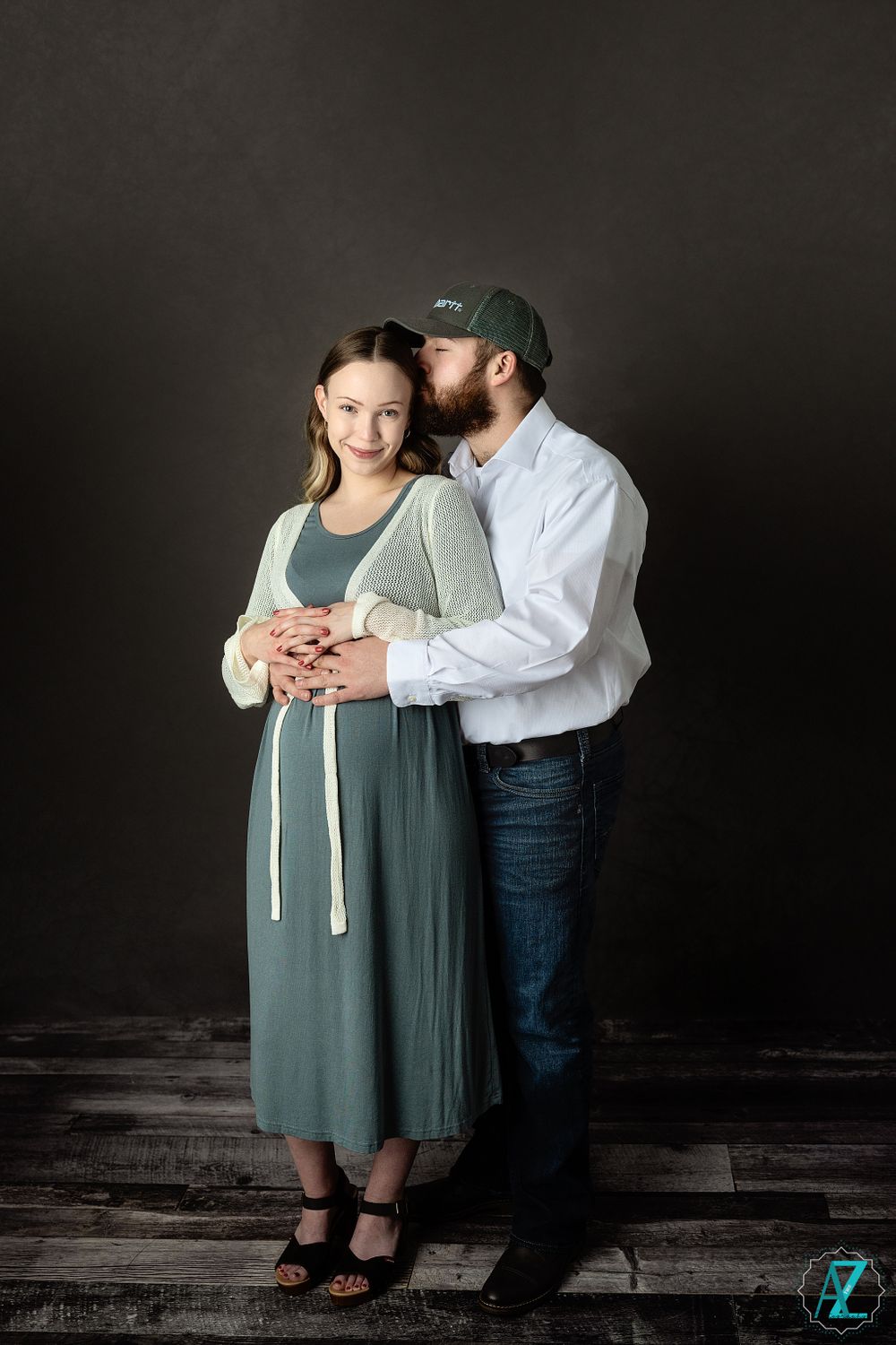 A tender embrace captured in a studio portrait against a dark background with moody lighting.