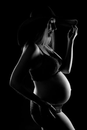 Dramatic silhouette of pregnant figure in black and white photography.