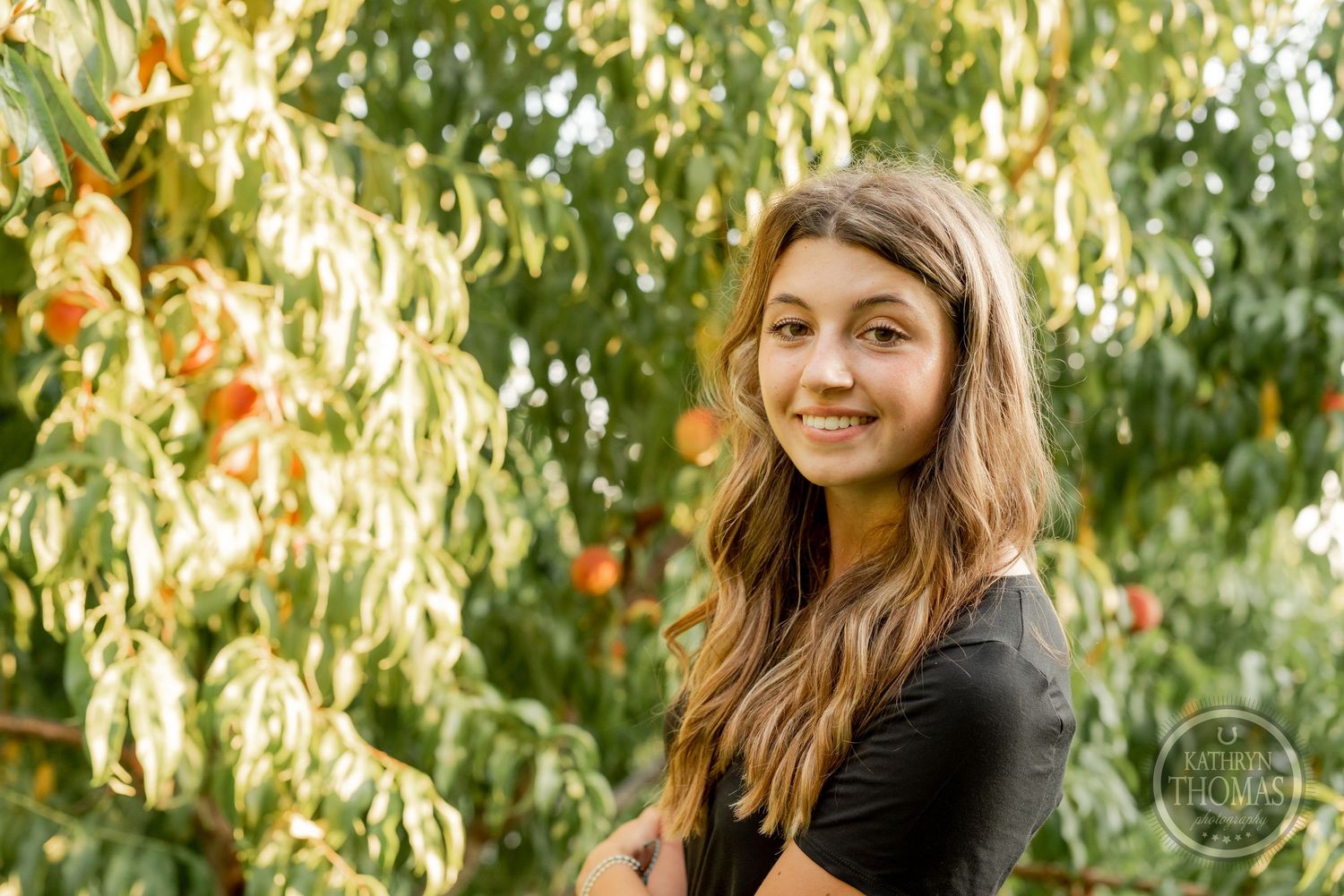 Natural outdoor portrait with peach trees and soft lighting in the background.