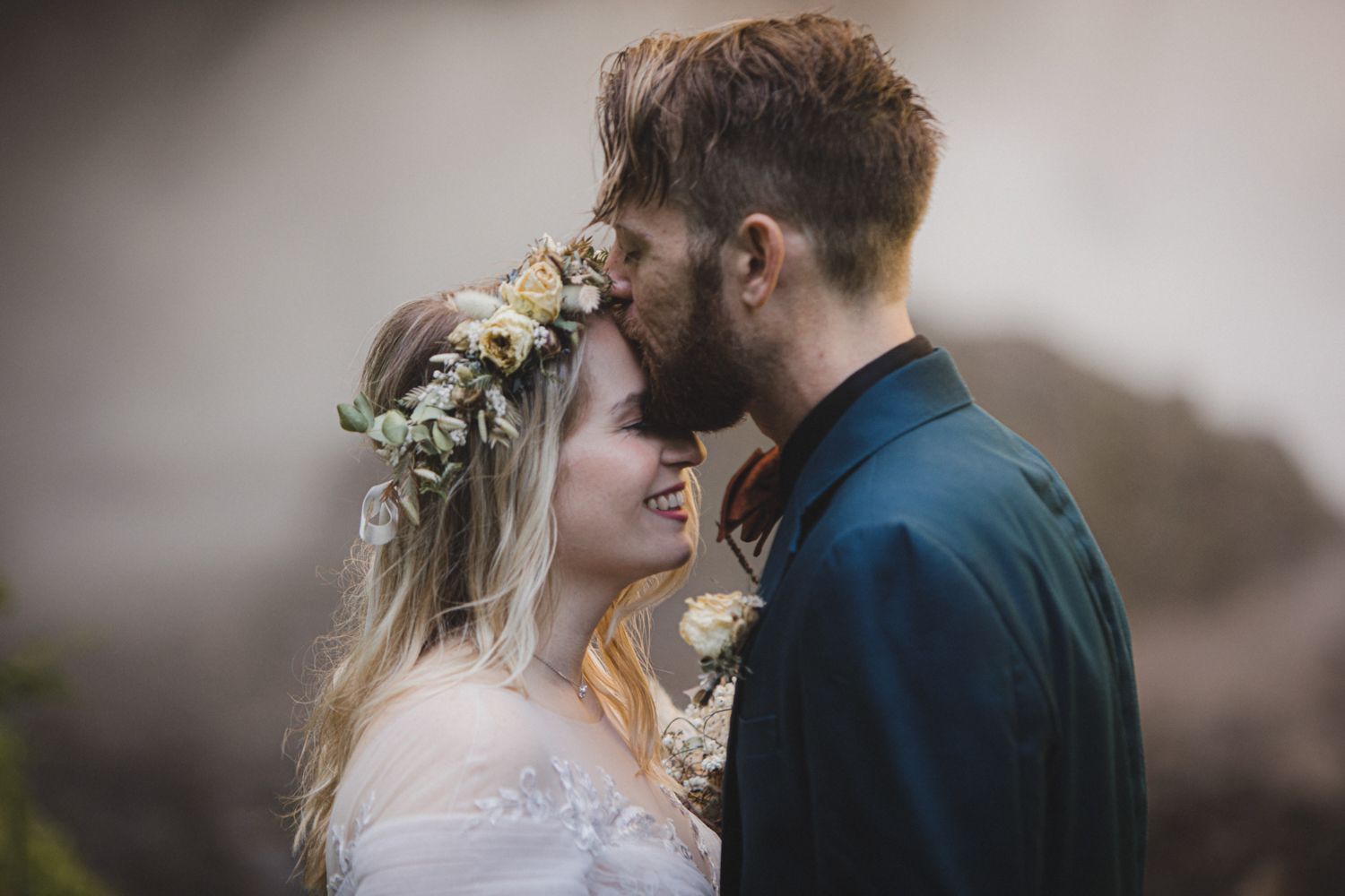 An intimate moment between a couple with flower crown against soft natural lighting.
