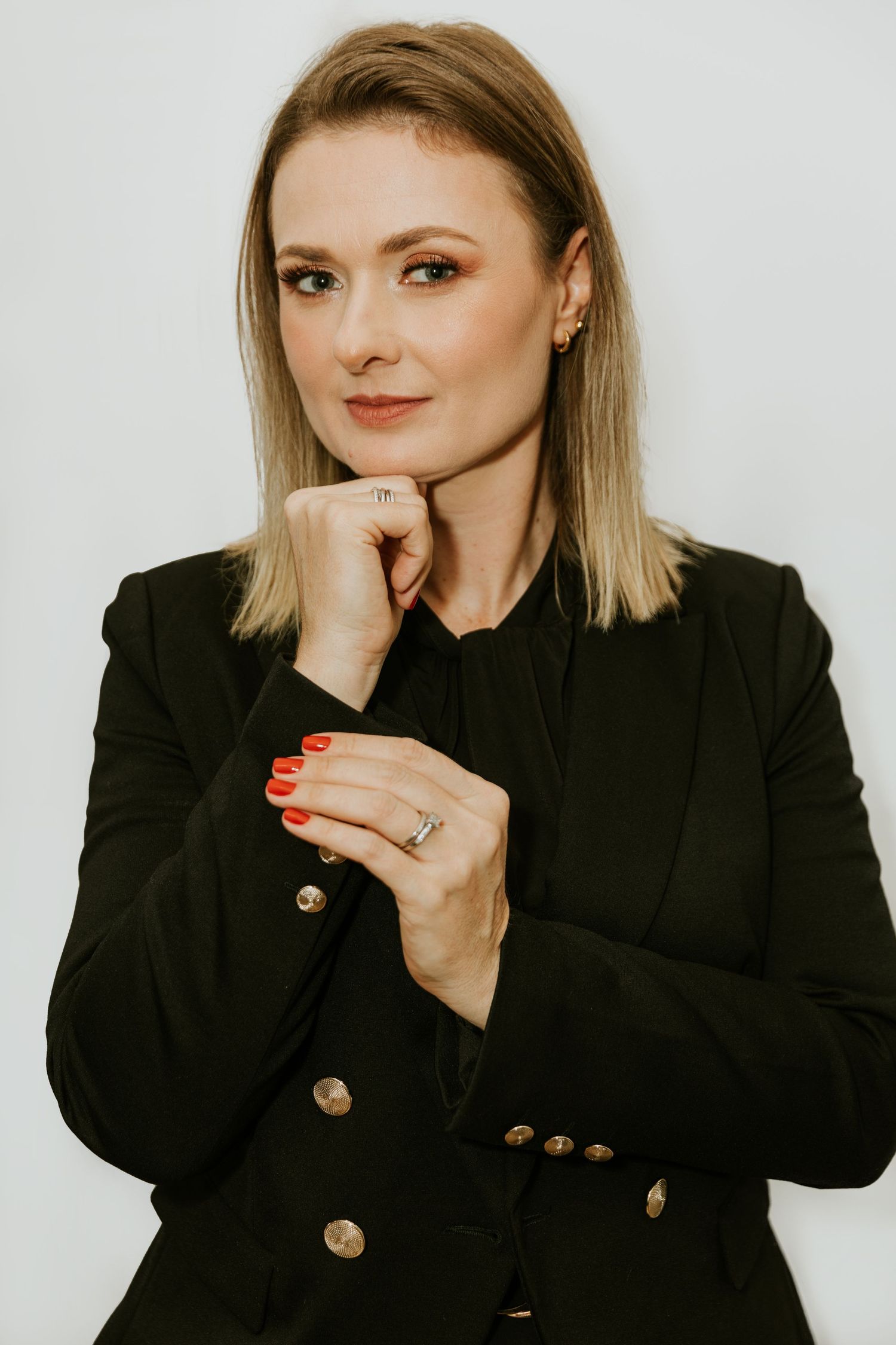 Professional headshot of woman in black blazer with blonde hair against white background.