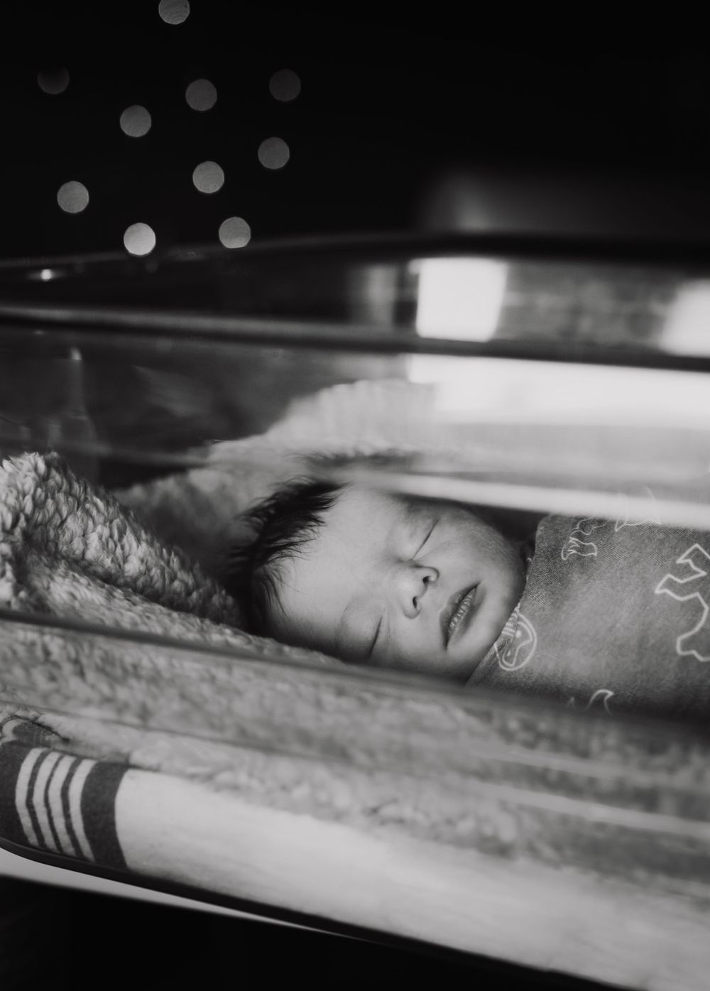 Artistic black and white portrait through glass with bokeh effects.