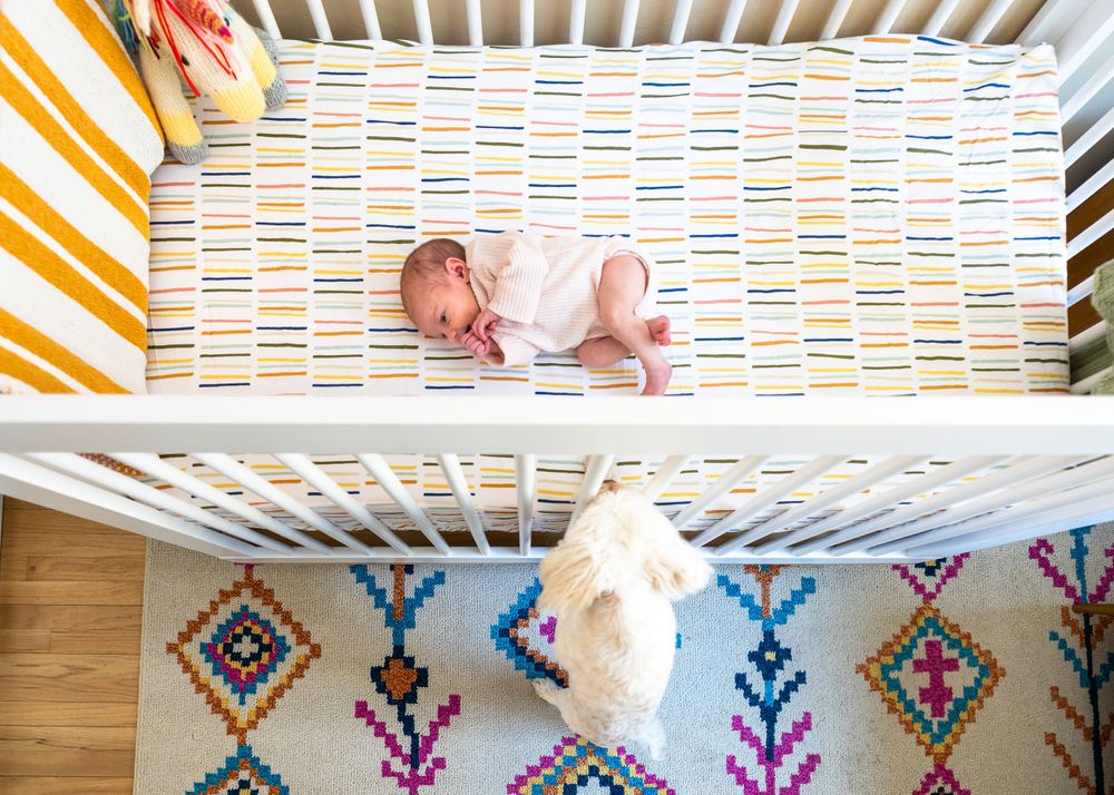Overhead view of sleeping baby in colorful patterned crib with geometric design bedding.