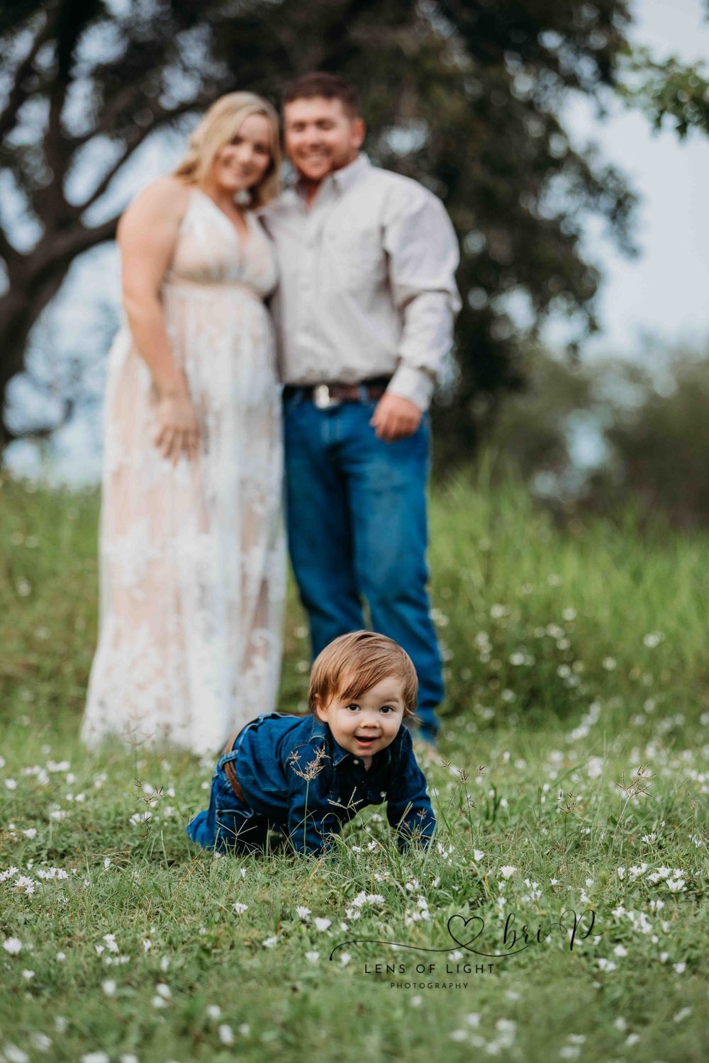 A candid family moment captured in a wildflower meadow on a sunny day.