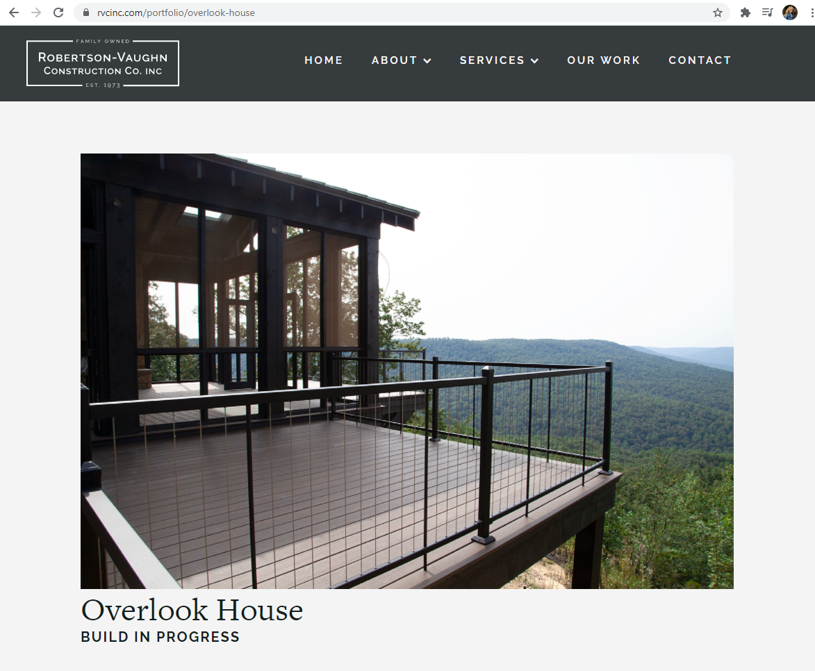 Scenic mountain overlook deck with glass railings and panoramic forest views.