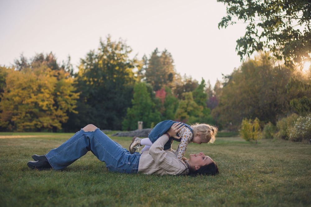 Family lying on grass together during fall season.