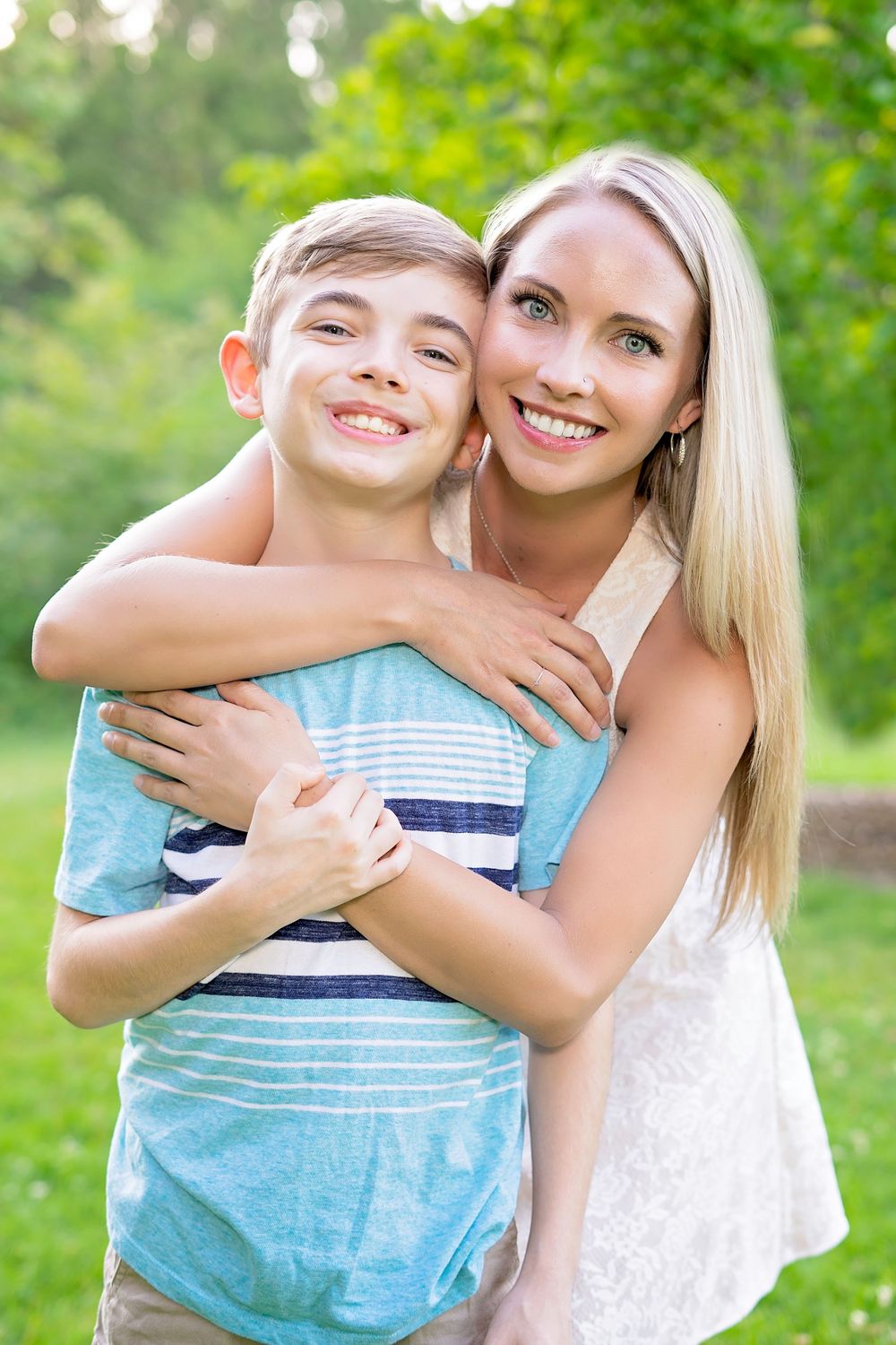 A warm embrace captured outdoors with lush green foliage in the background.