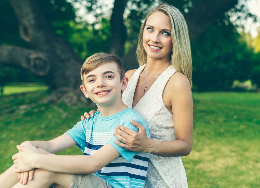A tender moment captured outdoors against a backdrop of green summer foliage.
