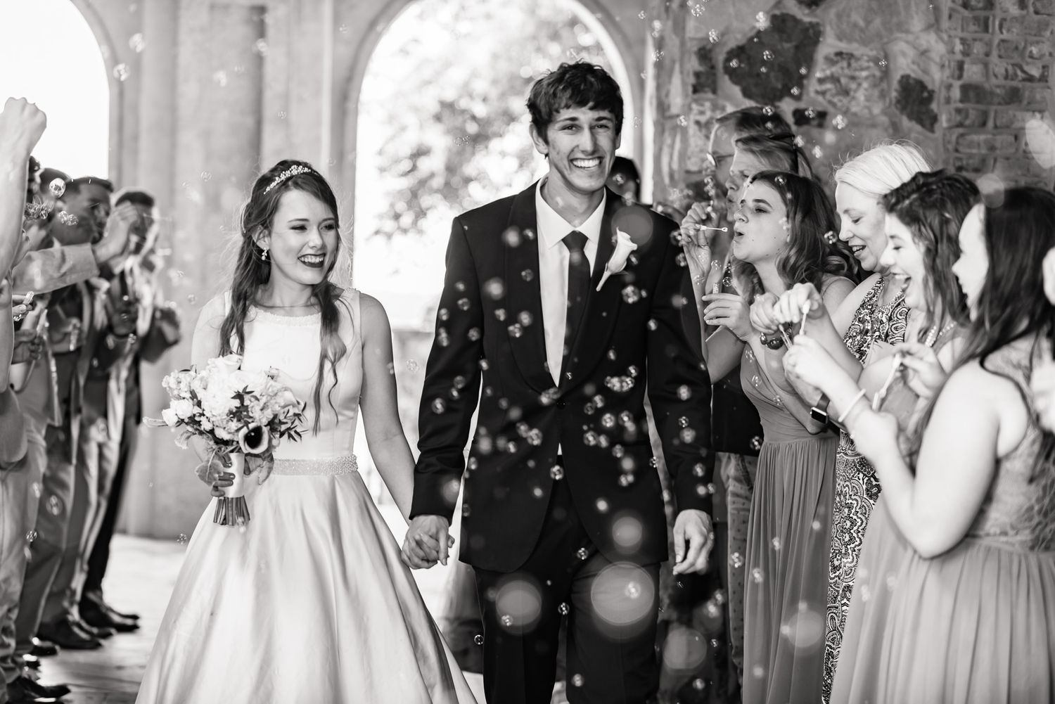 Smiling newlyweds make their exit as their family and friends excitedly blow bubbles at Bella Collina in Orlando, FL.