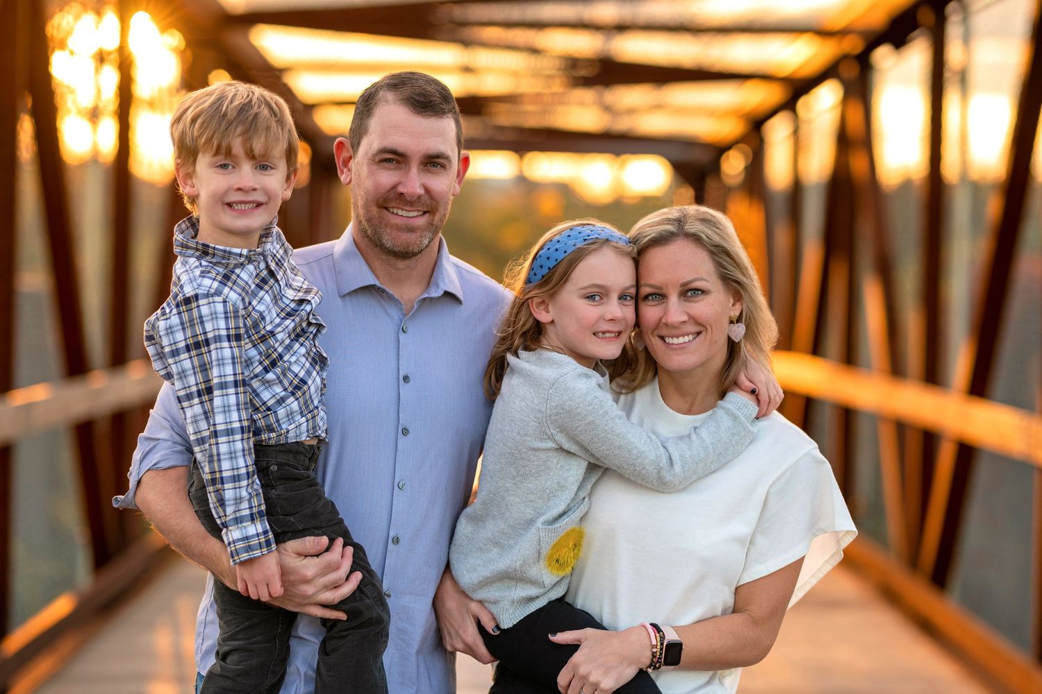 Family portrait on wooden bridge during golden sunset hour.