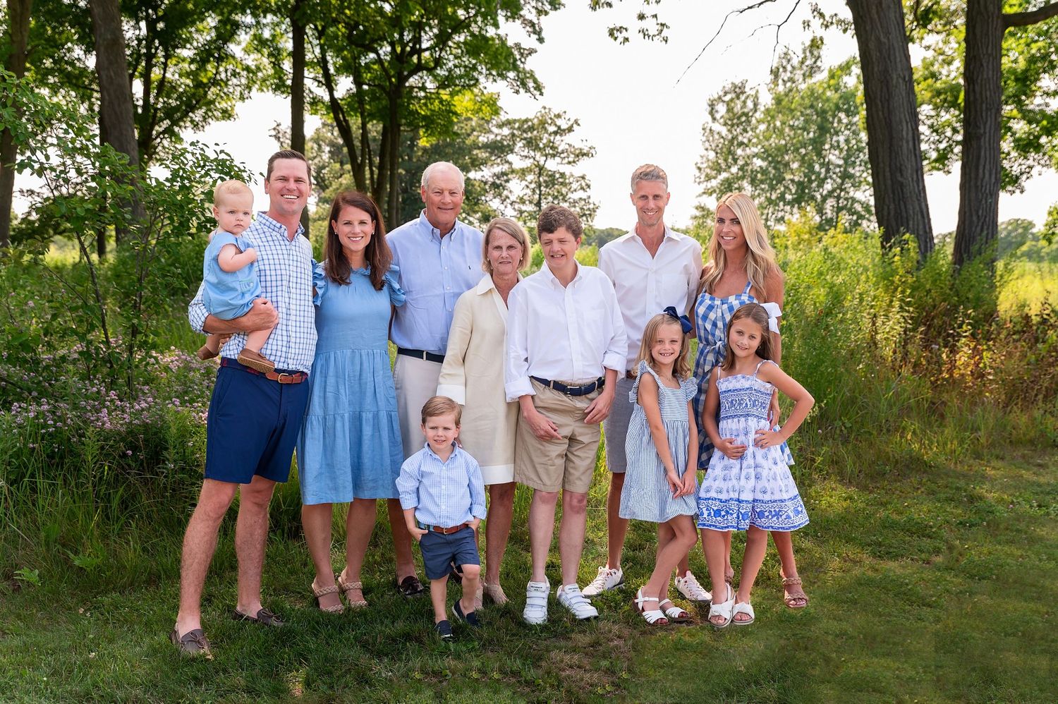 Extended family members in coordinated blue and white outfits pose together in a garden setting.