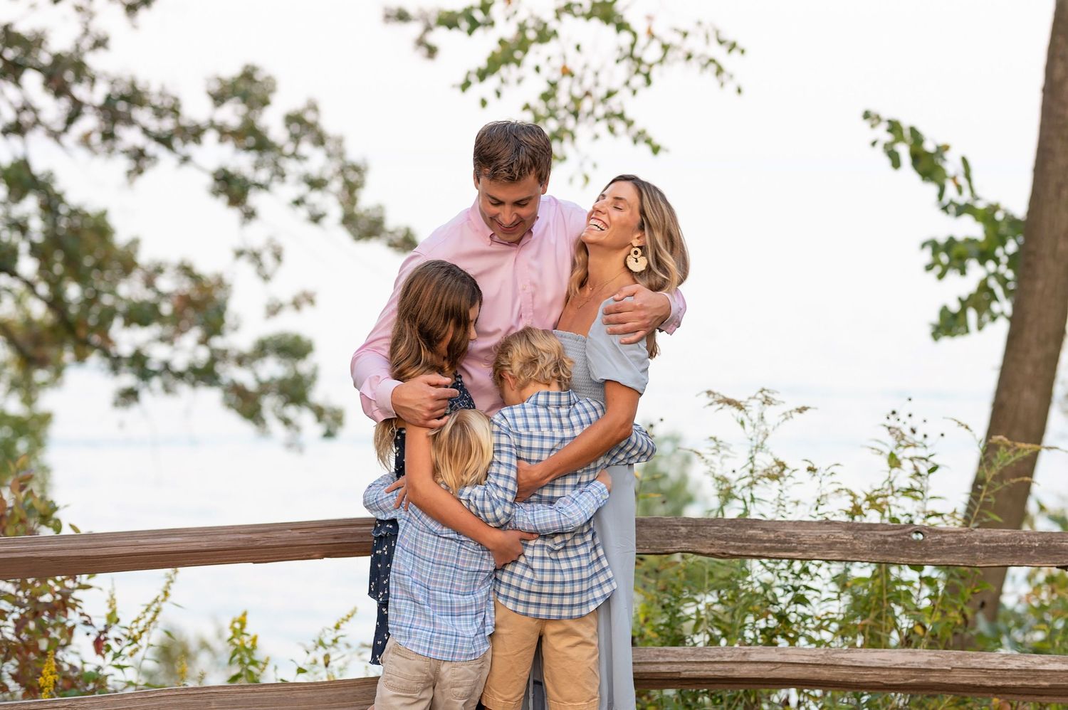 Family enjoying tender moment together on wooden deck overlooking scenic view.