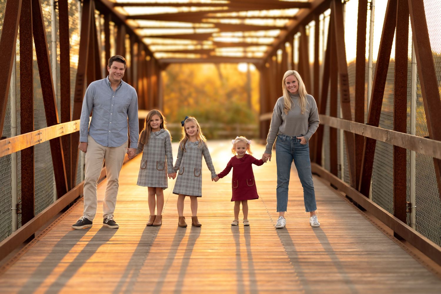 Group walking together on rustic wooden bridge during golden sunset hour.
