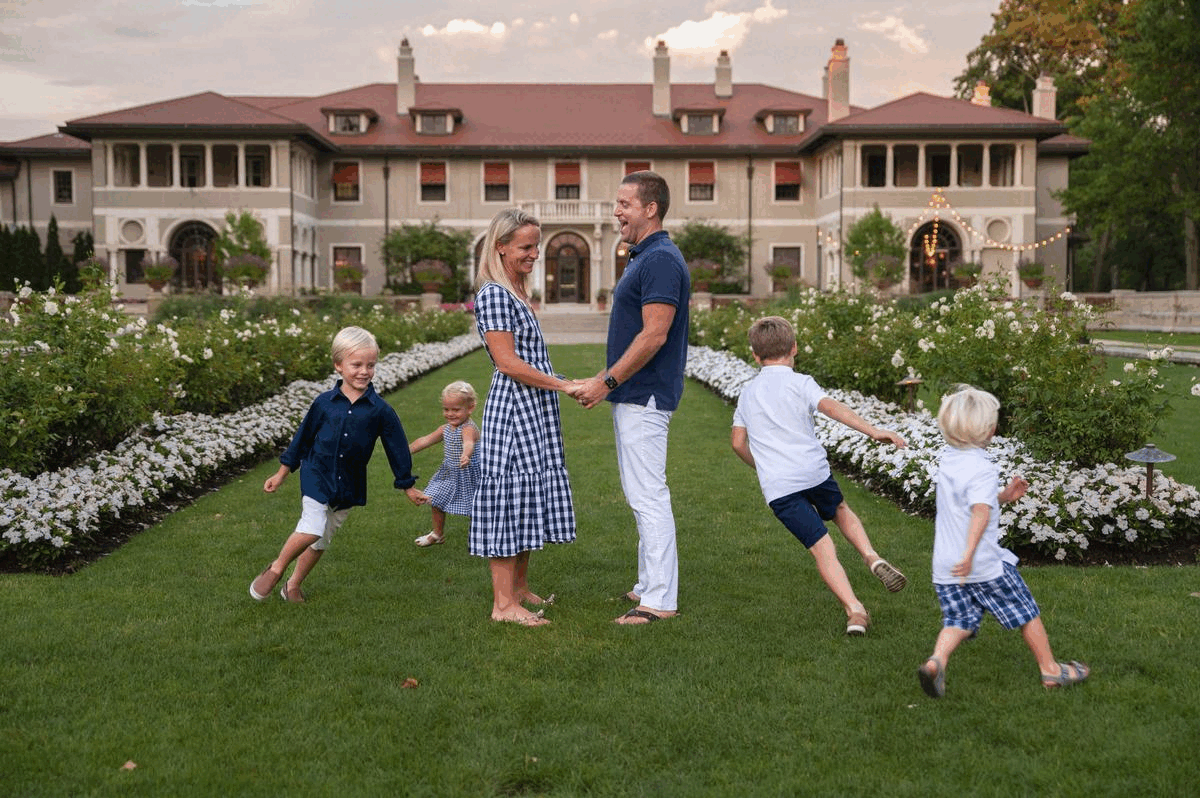 Couple standing while kids run around during fall photoshoot in garden.