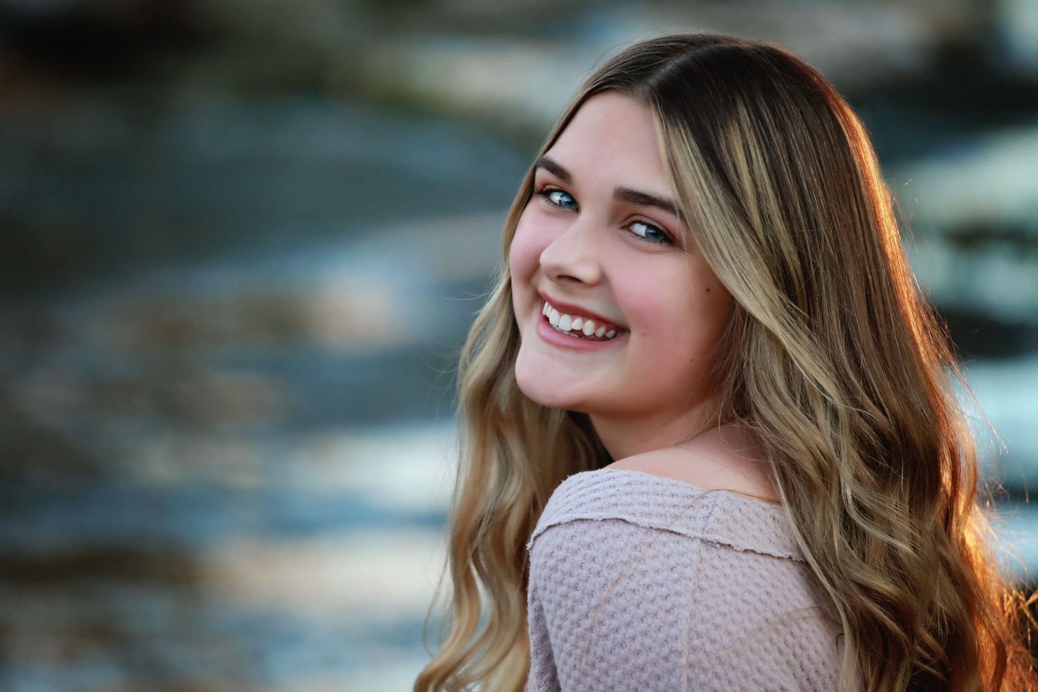 Professional senior portrait with soft golden light and natural scenery in background.