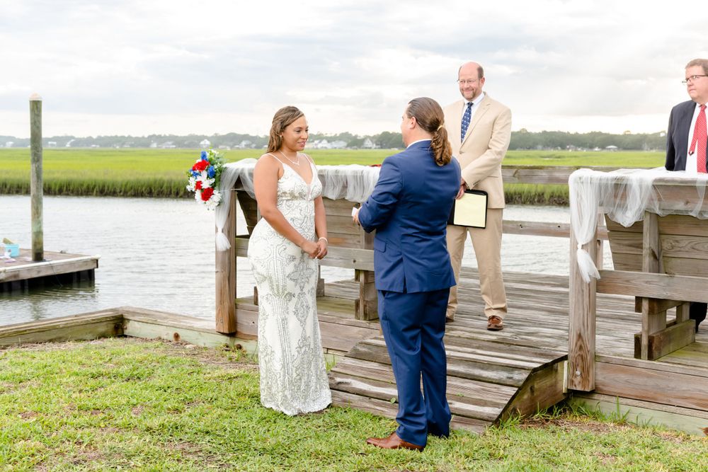 Waterfront dock wedding ceremony with marsh views and coastal landscape.