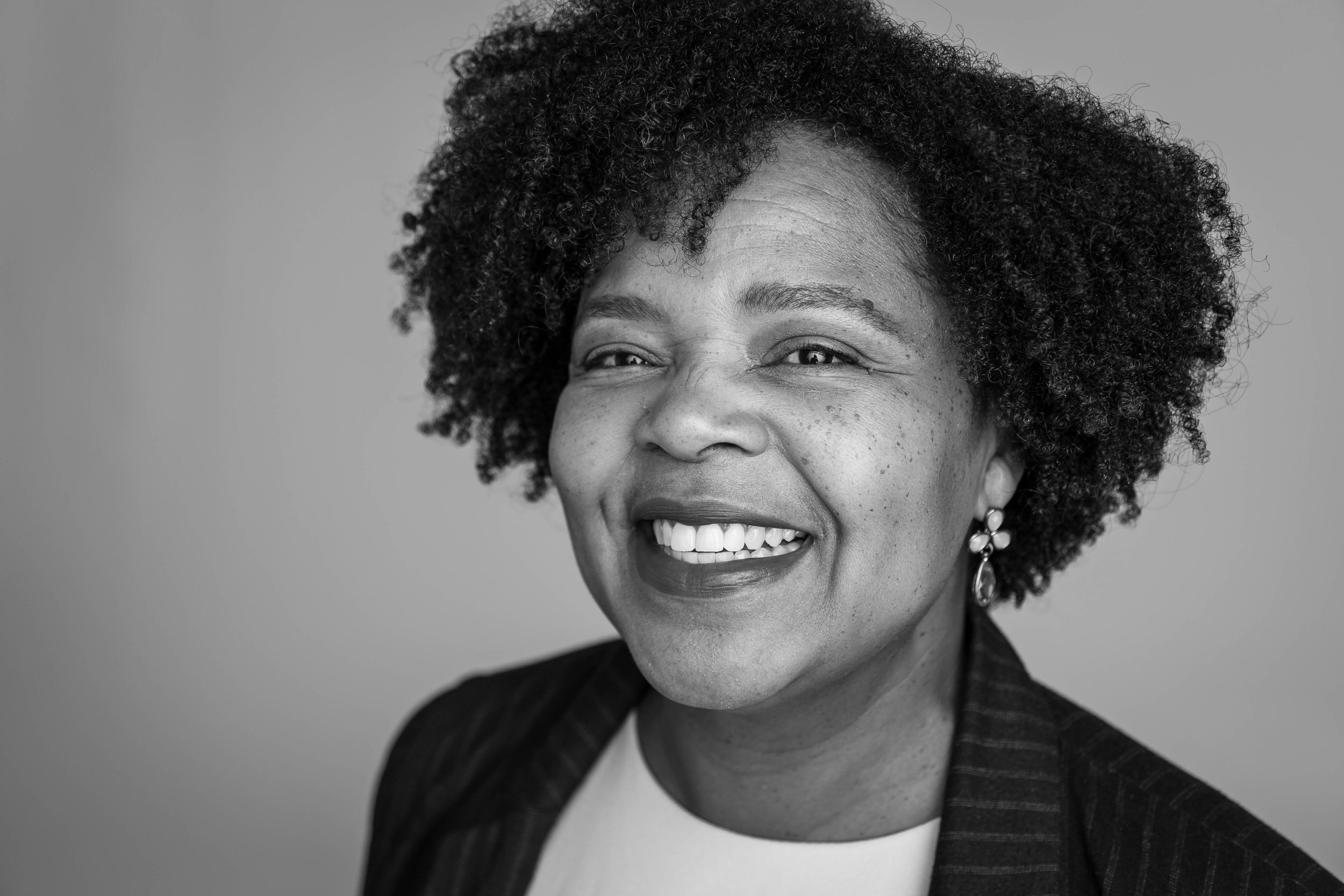Black and white portrait showing a joyful expression with natural curly hair.