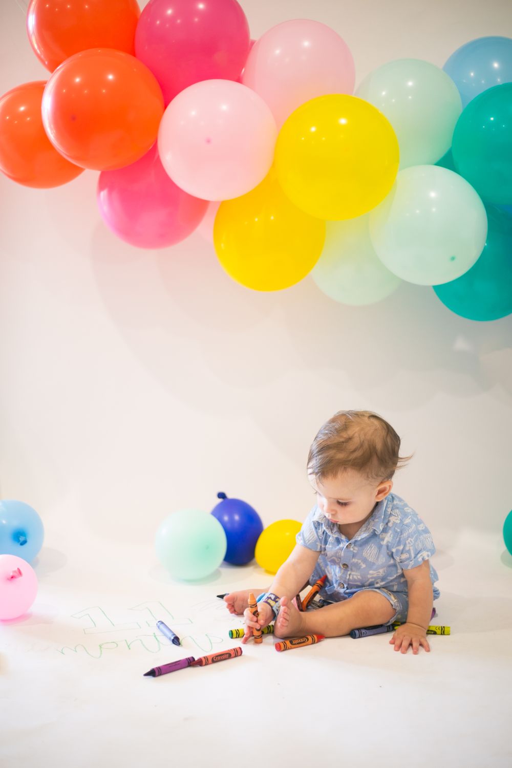 Harry with rainbow balloons drawing with crayons for his 11 month old photos