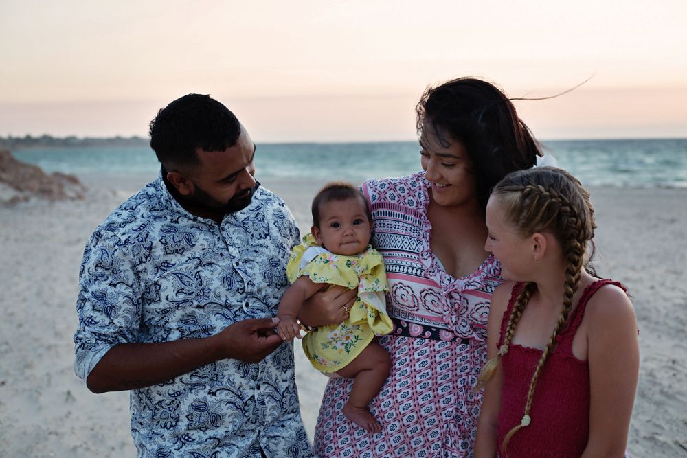 Aboriginal family on the beach cuddling together in Moonta Bay