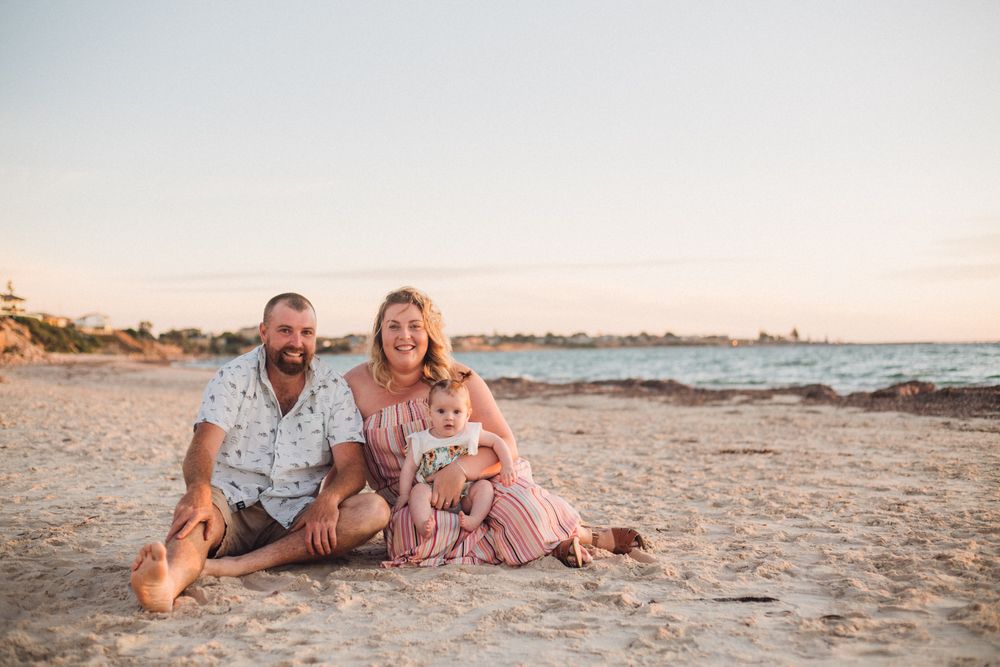 Dani redman, husband and her daughter sitting together cuddling on the beach at Moonta Bay