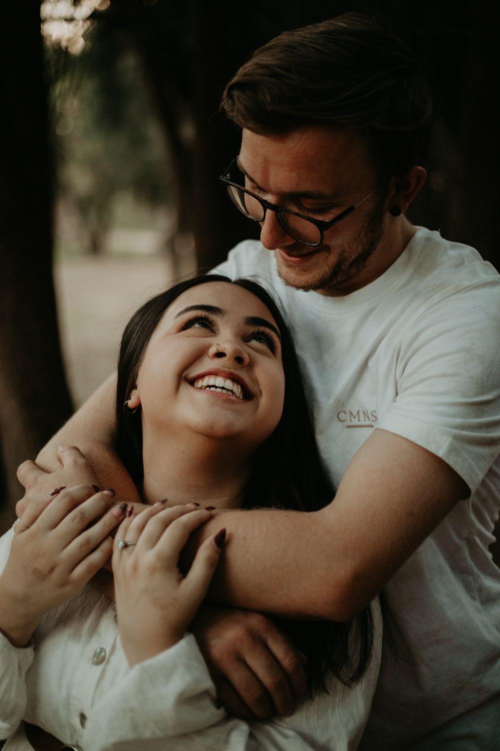 couple with mans arms wrapped around woman, smiling up at him lovingly