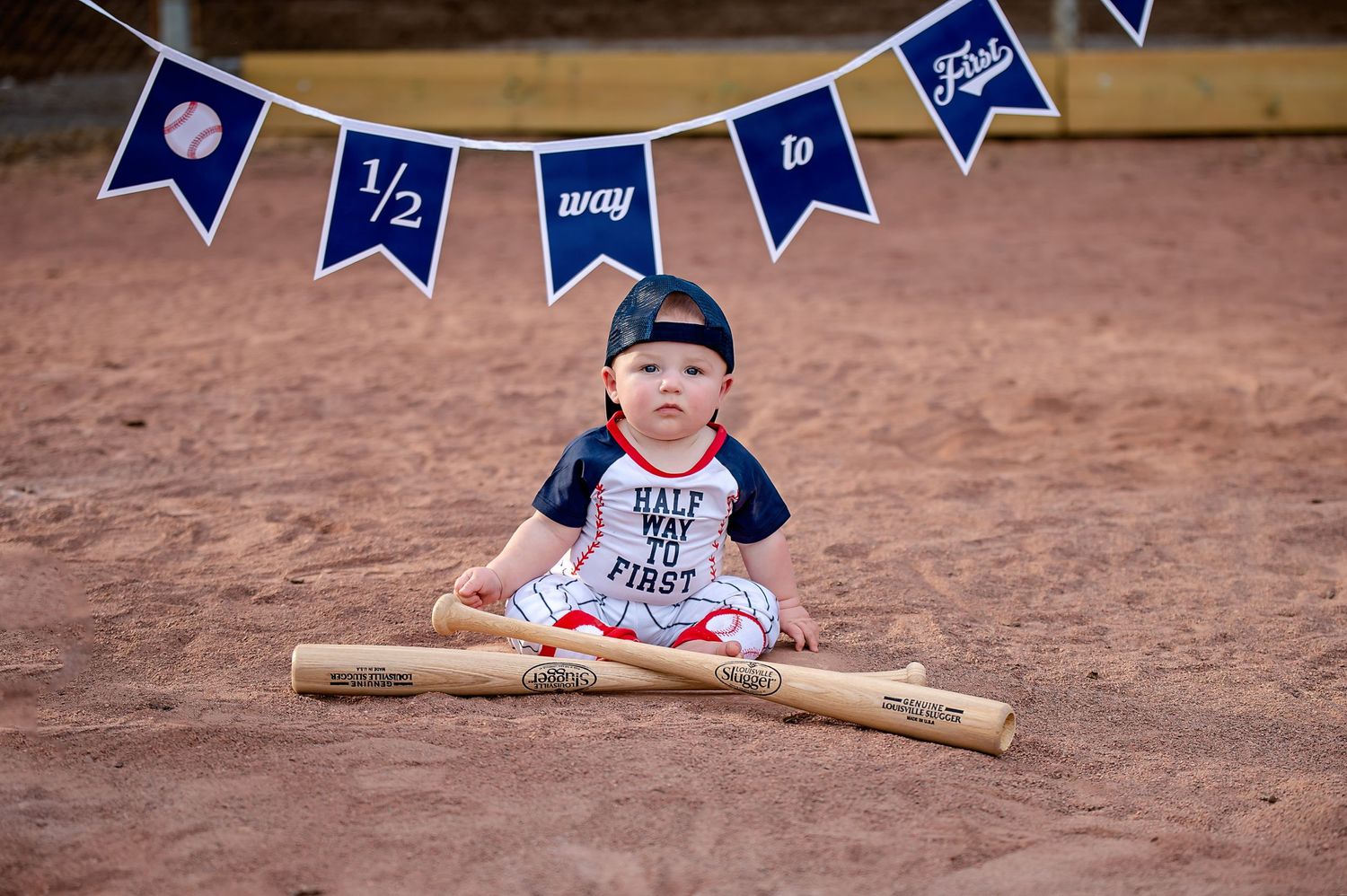 Baseball themed baby photo session with navy blue banners and wooden bat props.