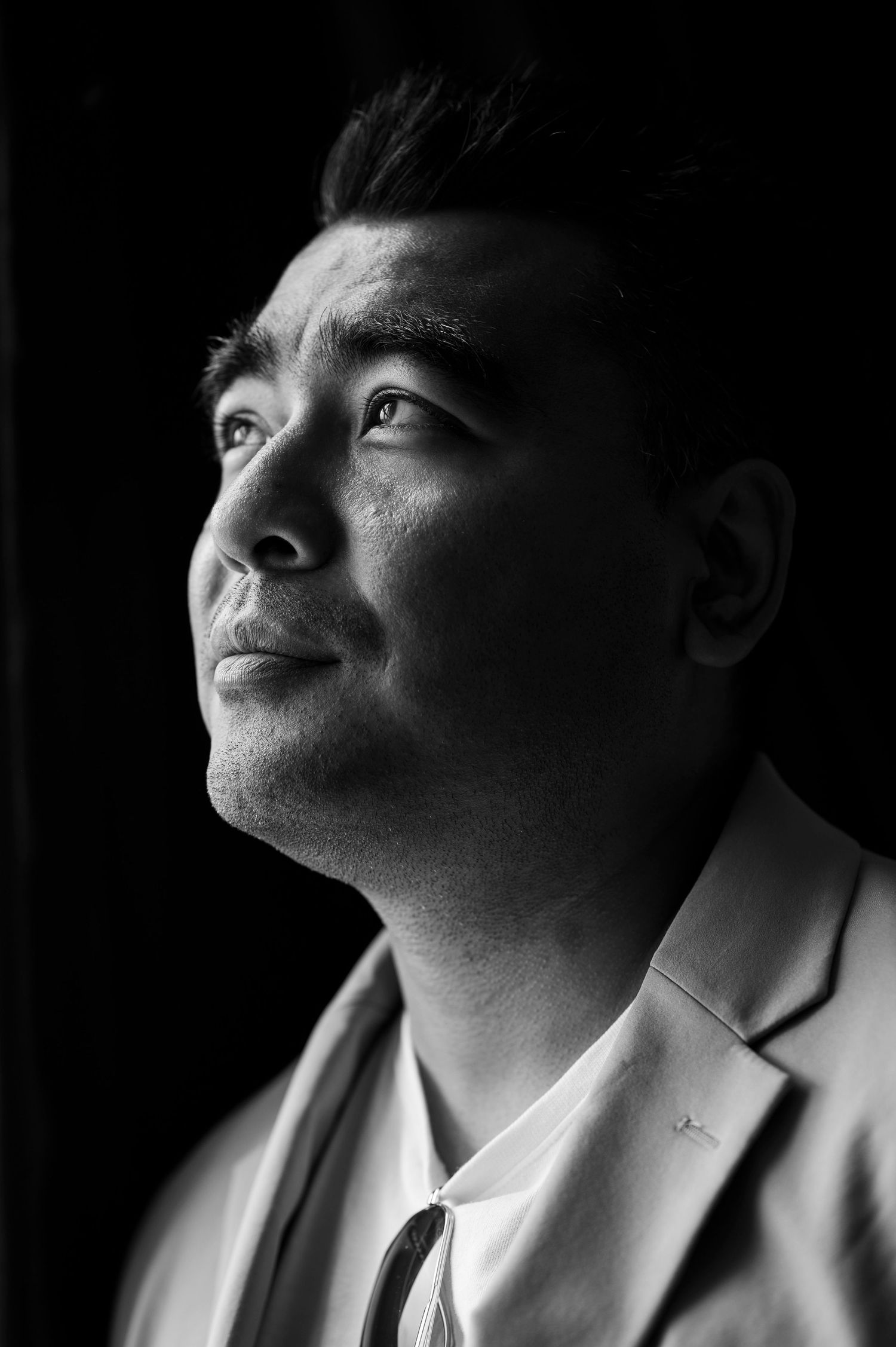 Black and white portrait of a man in a suit looking upward dramatically.