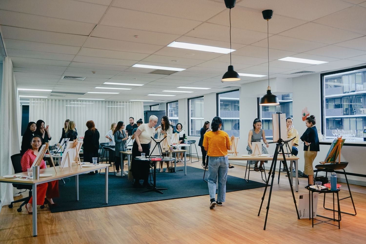 Art students working together in a bright modern studio classroom with easels and workstations.