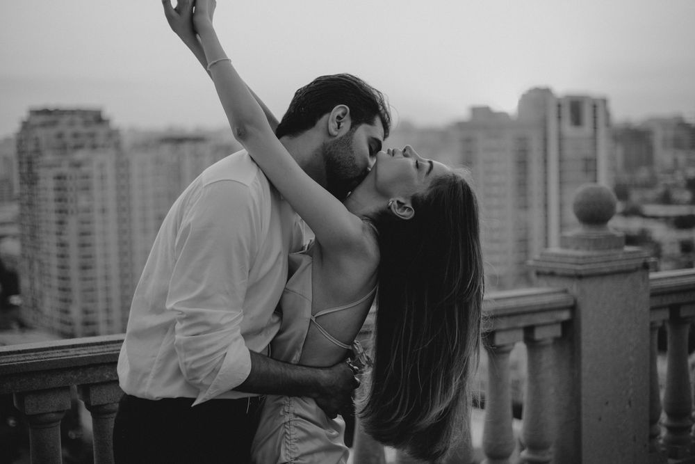 Romantic black and white moment captured on rooftop balcony with city backdrop.
