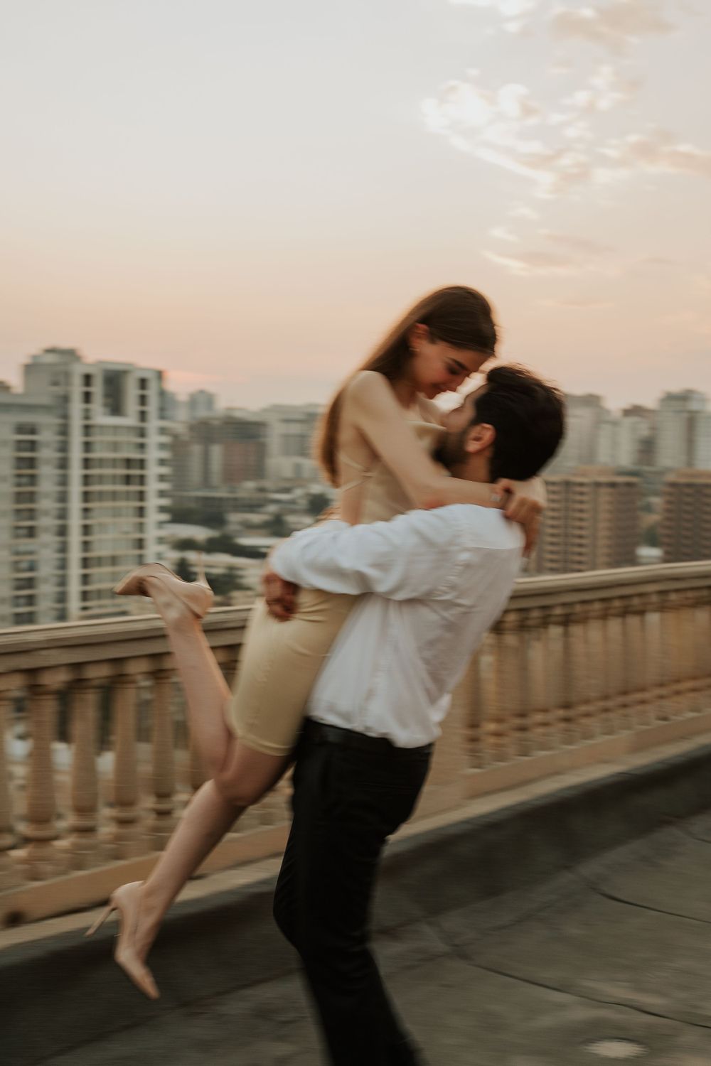 Romantic sunset moment with couple dancing on rooftop terrace overlooking cityscape.