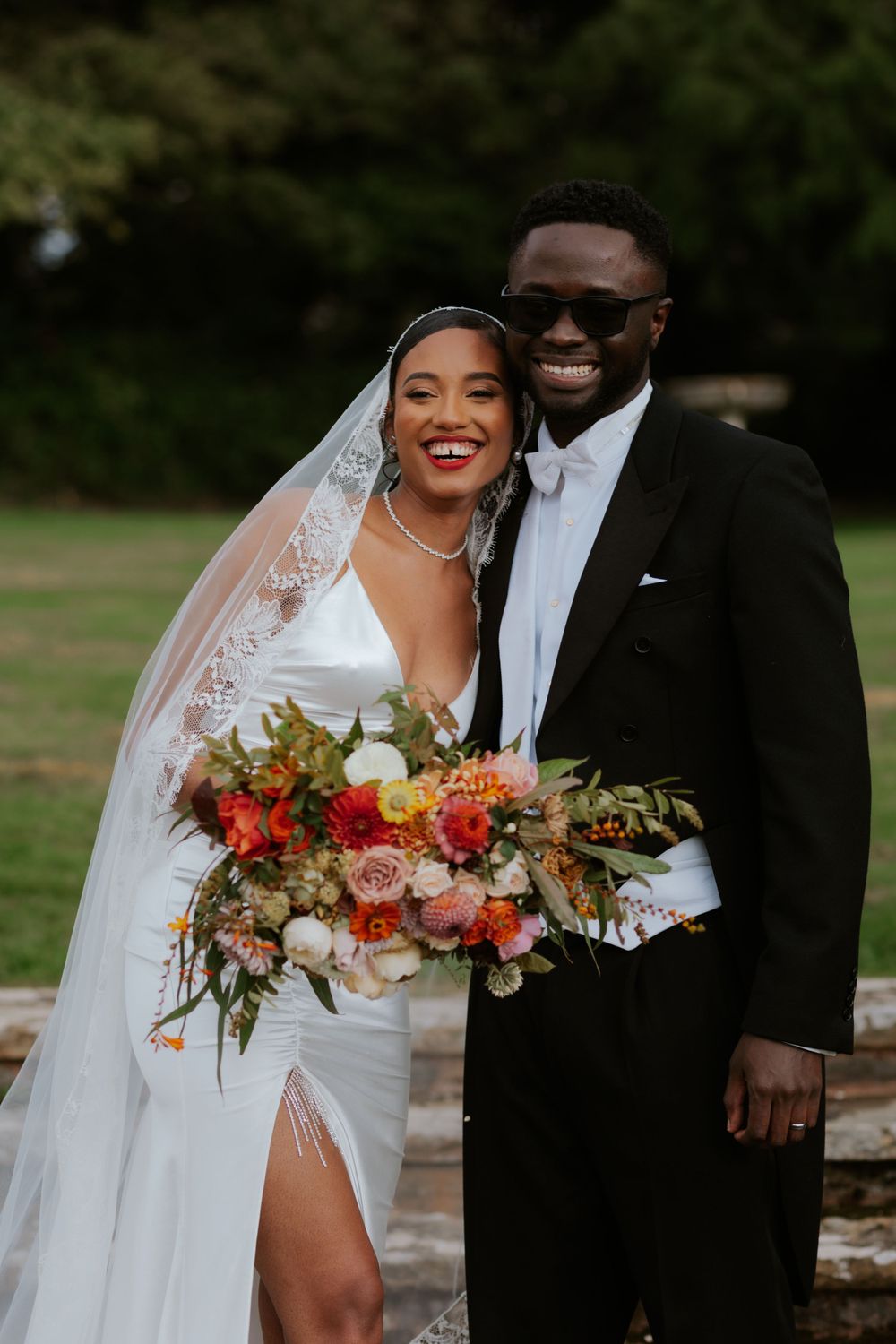 Joyful wedding portrait with stunning floral bouquet and classic formal attire.