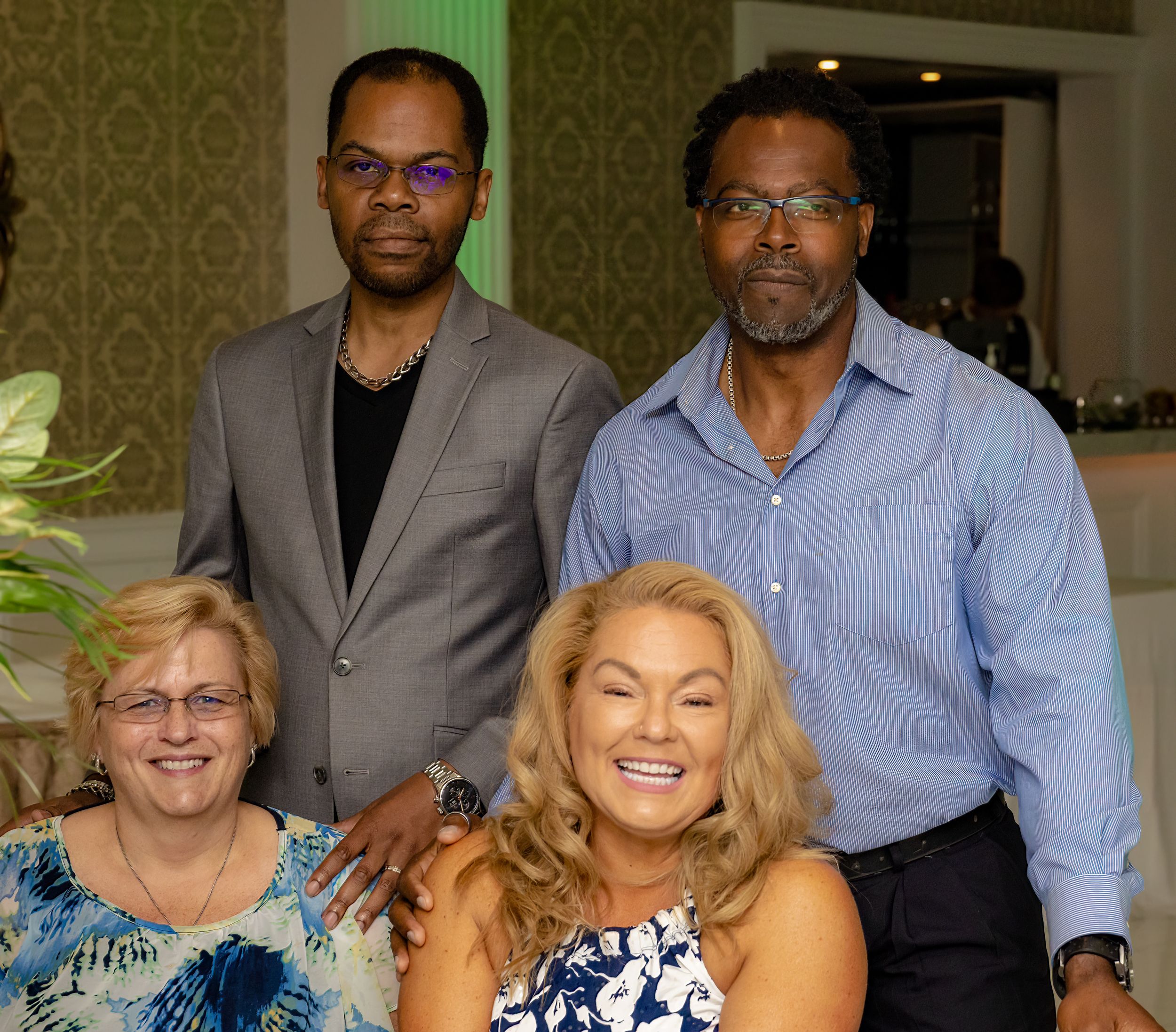 Formal group photo of event guests in elegant attire at an indoor venue.